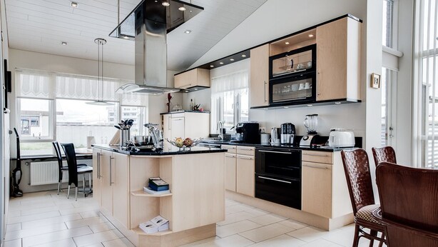 A modern kitchen with a central island, built-in appliances, and ample natural light. - Guesthouse Bjarney (Selfoss)