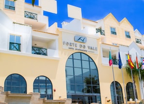 A hotel facade with large arched windows, balconies, and multiple flags. - Grand Muthu Forte do Vale (Albufeira)
