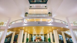 Un atrio de varios niveles con una zona de recepción central, barandillas de vidrio y un diseño arquitectónico moderno.