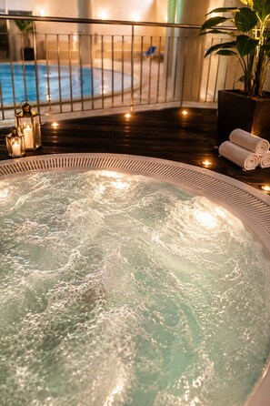A hot tub with a railing, a potted plant, and a pool in the background. - Grand Muthu Forte do Vale (Albufeira)