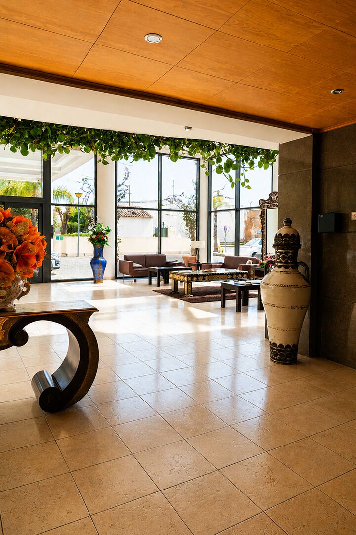 A spacious lobby with a wooden ceiling, large windows, and a seating area with tables and chairs.