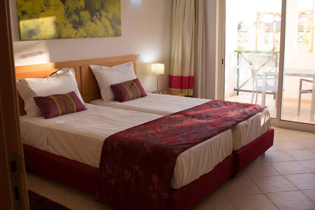 Une chambre d’hôtel avec deux lits, une vue sur l’extérieur et une table avec des chaises près de la fenêtre.