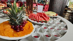 Un bufé con diversas frutas y tazas blancas, probablemente para bebidas.
