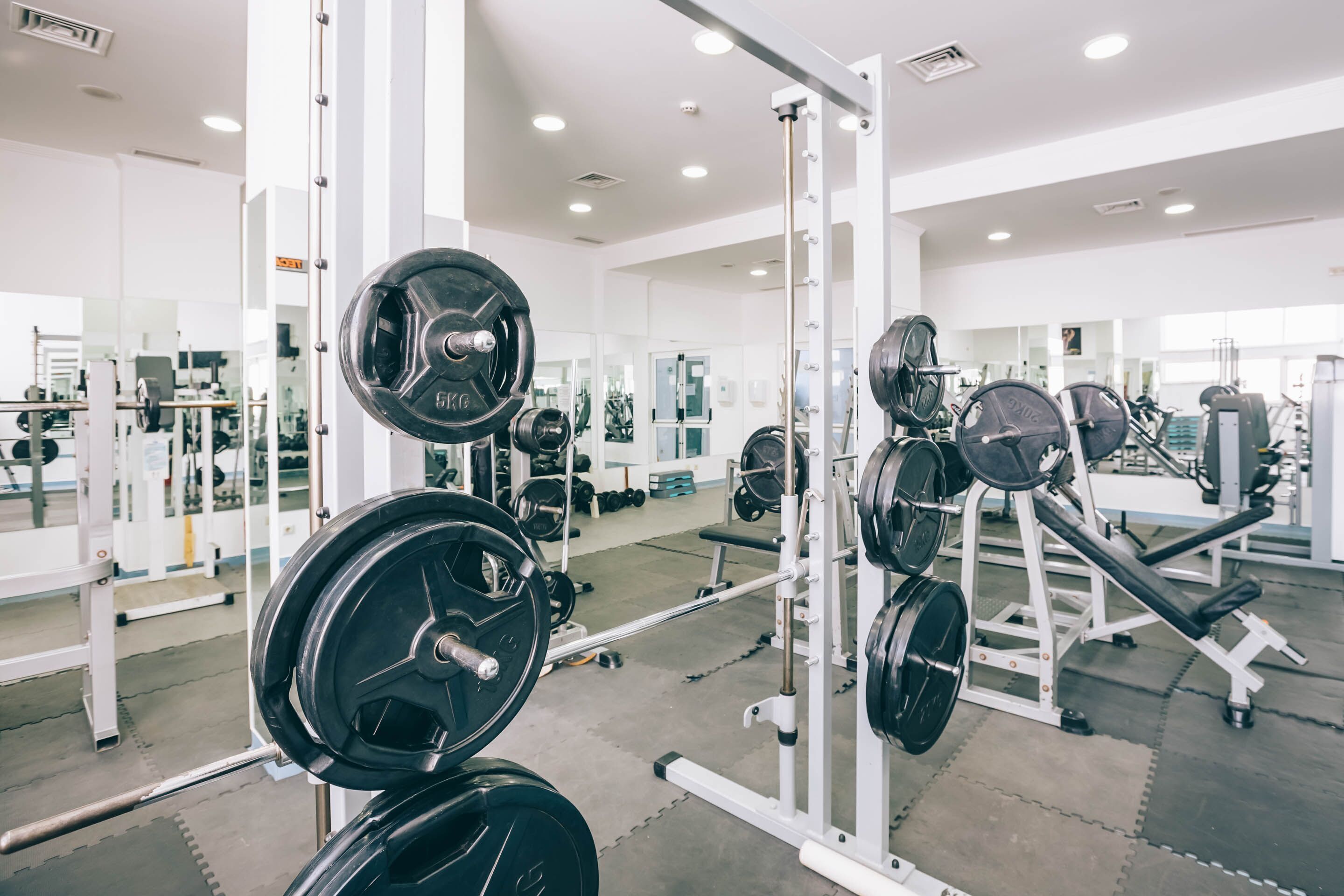 A gym with weightlifting equipment, mirrors, and a clean, modern design.