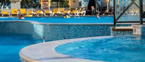 Una piscina cubierta, una piscina al aire libre, sombrillas, tumbonas