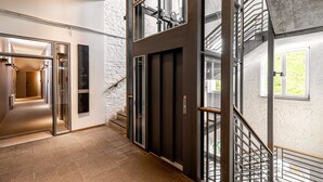 A modern interior with a staircase, elevator, and a hallway leading to another room. - YoHo - the young hotel (Hamburg)