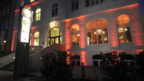 A building with arched windows and a staircase leading to the entrance. - YoHo - the young hotel (Hamburg)
