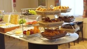 Un buffet proposant une variété de plats, notamment des fruits, des pâtisseries et du pain.