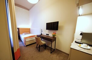 Una camera d'albergo con un letto, una scrivania, una sedia, una televisione e una macchina per il caffè.