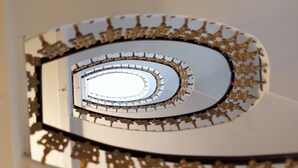 Un escalier en colimaçon doté d’une surface réfléchissante et de détails dorés.