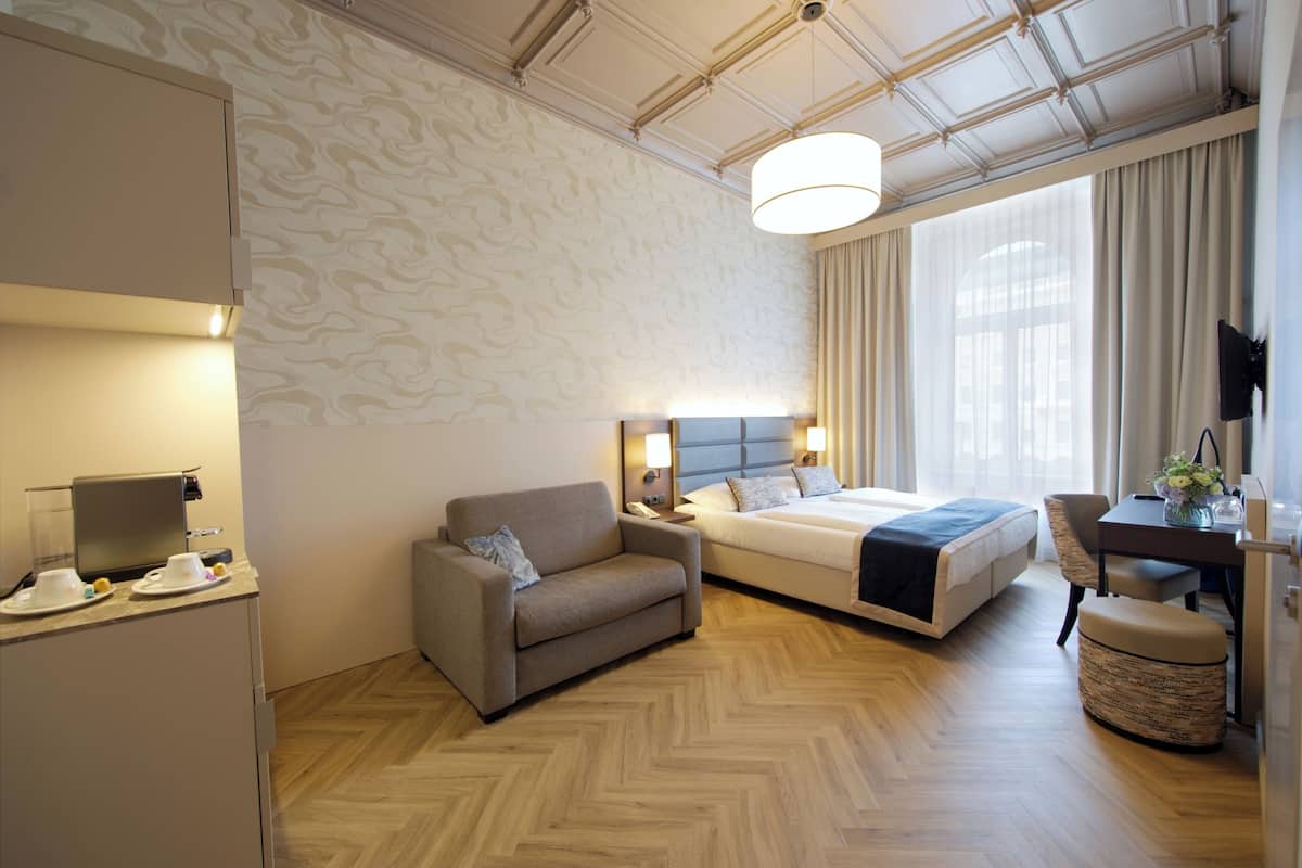 Una habitación de hotel con cama, sofá, escritorio y televisión.