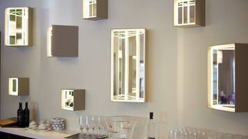 Un espace bar agrémenté de plusieurs appliques murales illuminées, d’une sélection de bouteilles de vin et d’une variété de verres à vin.