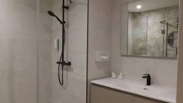 A modern bathroom with a glass-enclosed shower, a white sink, and a mirror above the vanity.