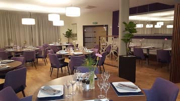 Un restaurante con mesas redondas, sillas moradas y vajilla blanca.