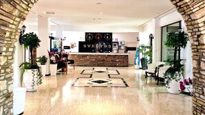 A lobby with a stone archway, a reception desk, and potted plants. - Sveltos Hotel (Oroklini)