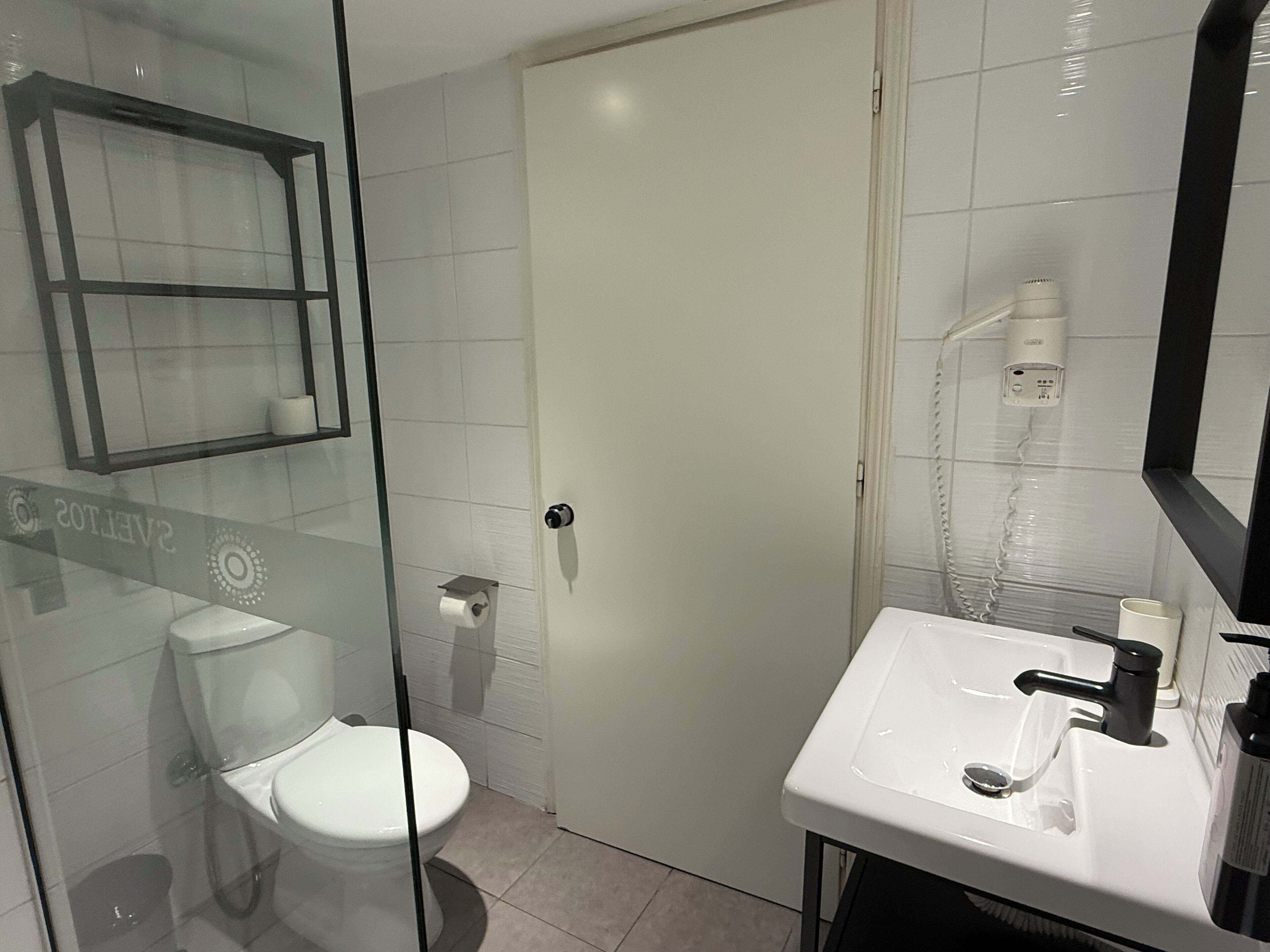 A modern bathroom with a glass shower enclosure, a toilet, a sink with a mirror, and a towel rack.