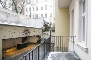 A balcony with a tiled floor, a black metal railing, and a string of lights. - Numa Prague Flow (Prague)