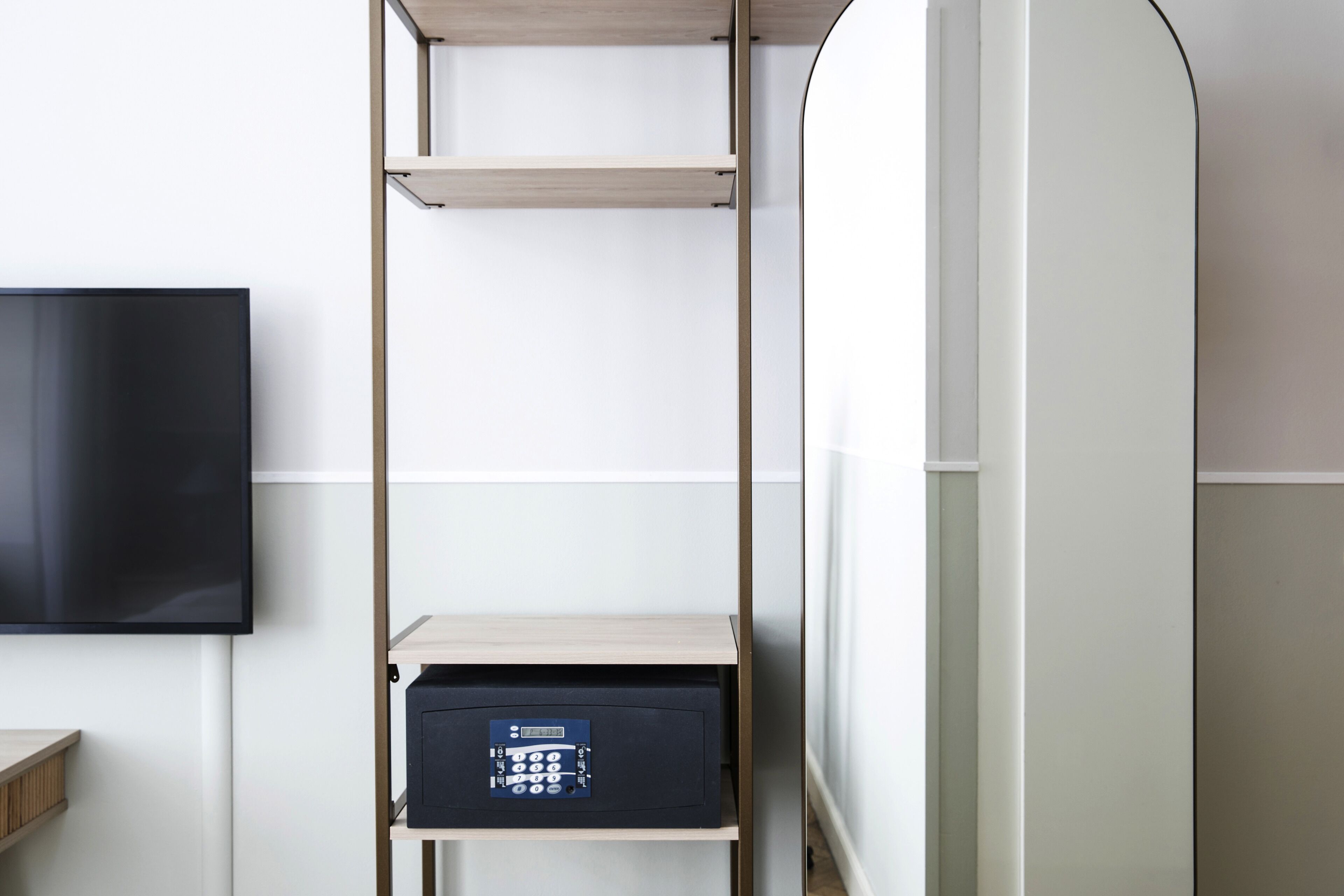 Une pièce dotée d’un téléviseur à écran plat fixé au mur, d’une étagère en bois avec un panneau de commande et d’un mur blanc.