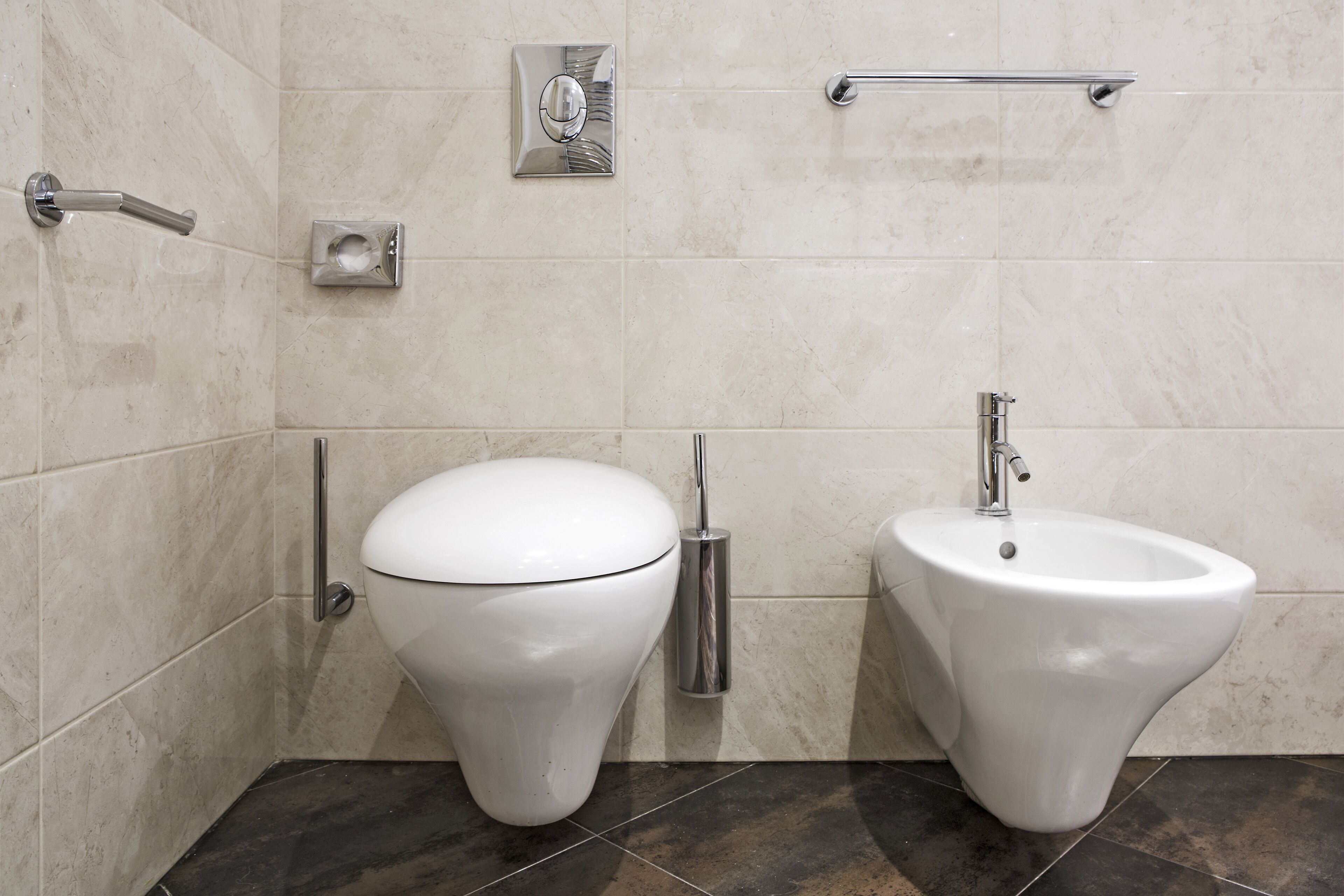 A modern bathroom with a toilet, bidet, and a hand dryer.