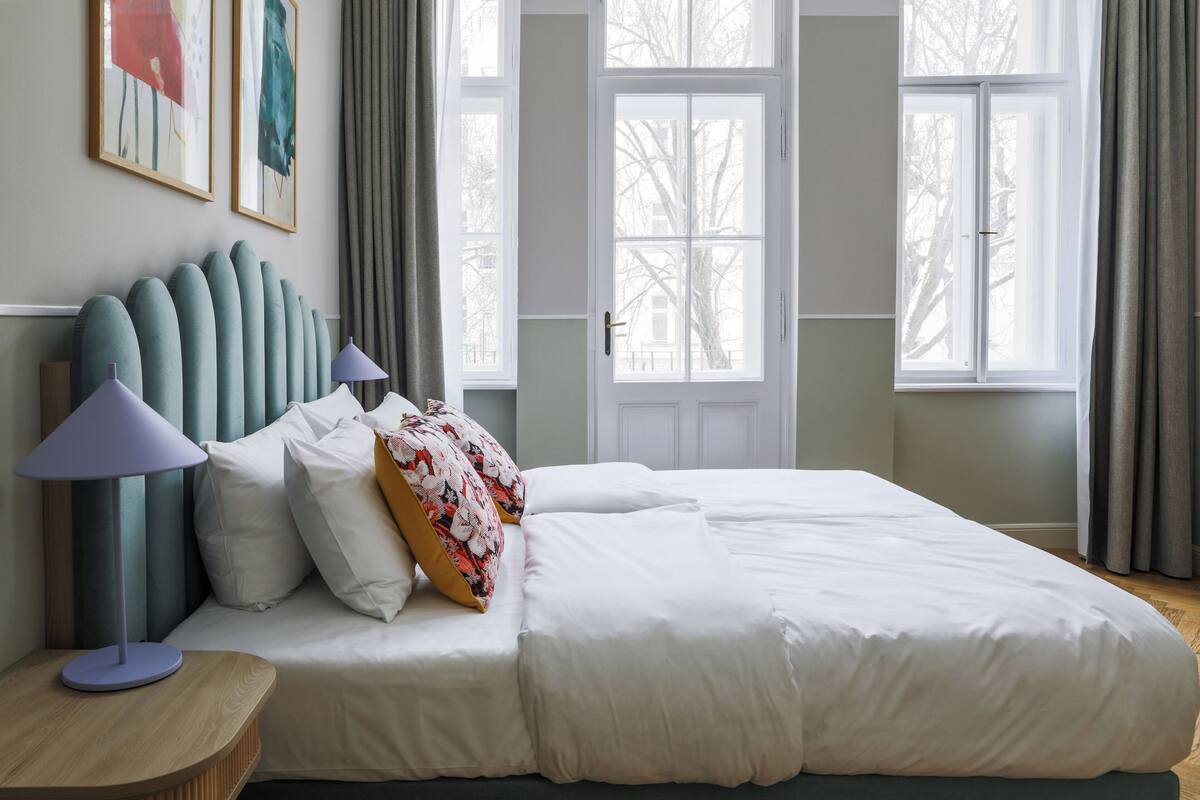 A neatly made bed with white bedding, a headboard with vertical lines, and two bedside lamps.