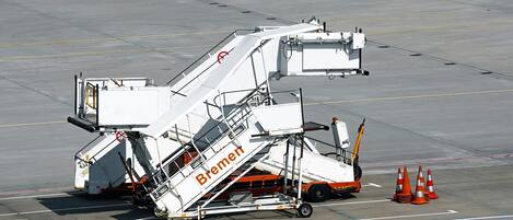 Un système de manutention des bagages portant la mention « Bremen », situé sur l’aire de stationnement d’un aéroport.
