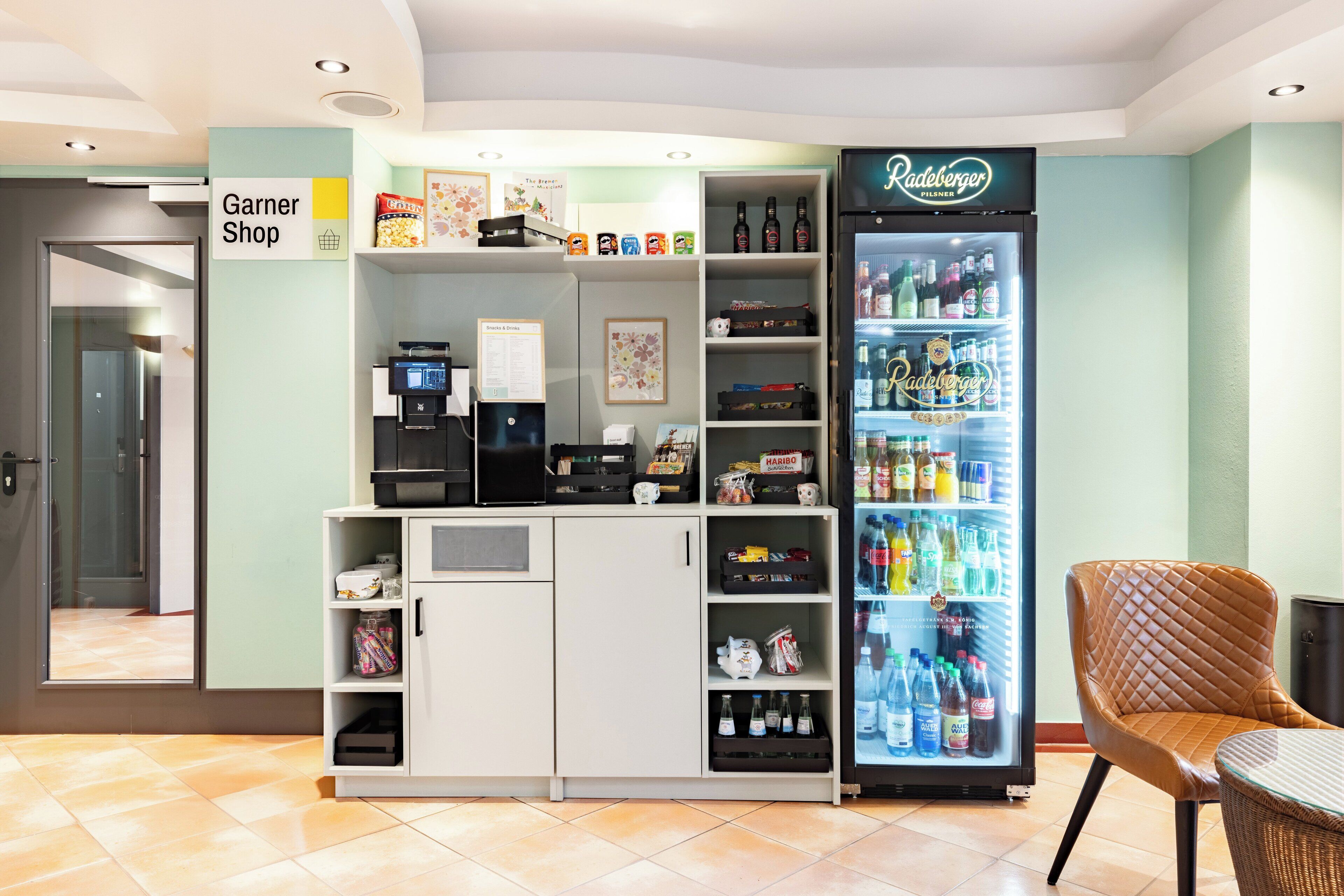 A vending machine area with a refrigerator stocked with beverages, a coffee machine, and a snack shelf.