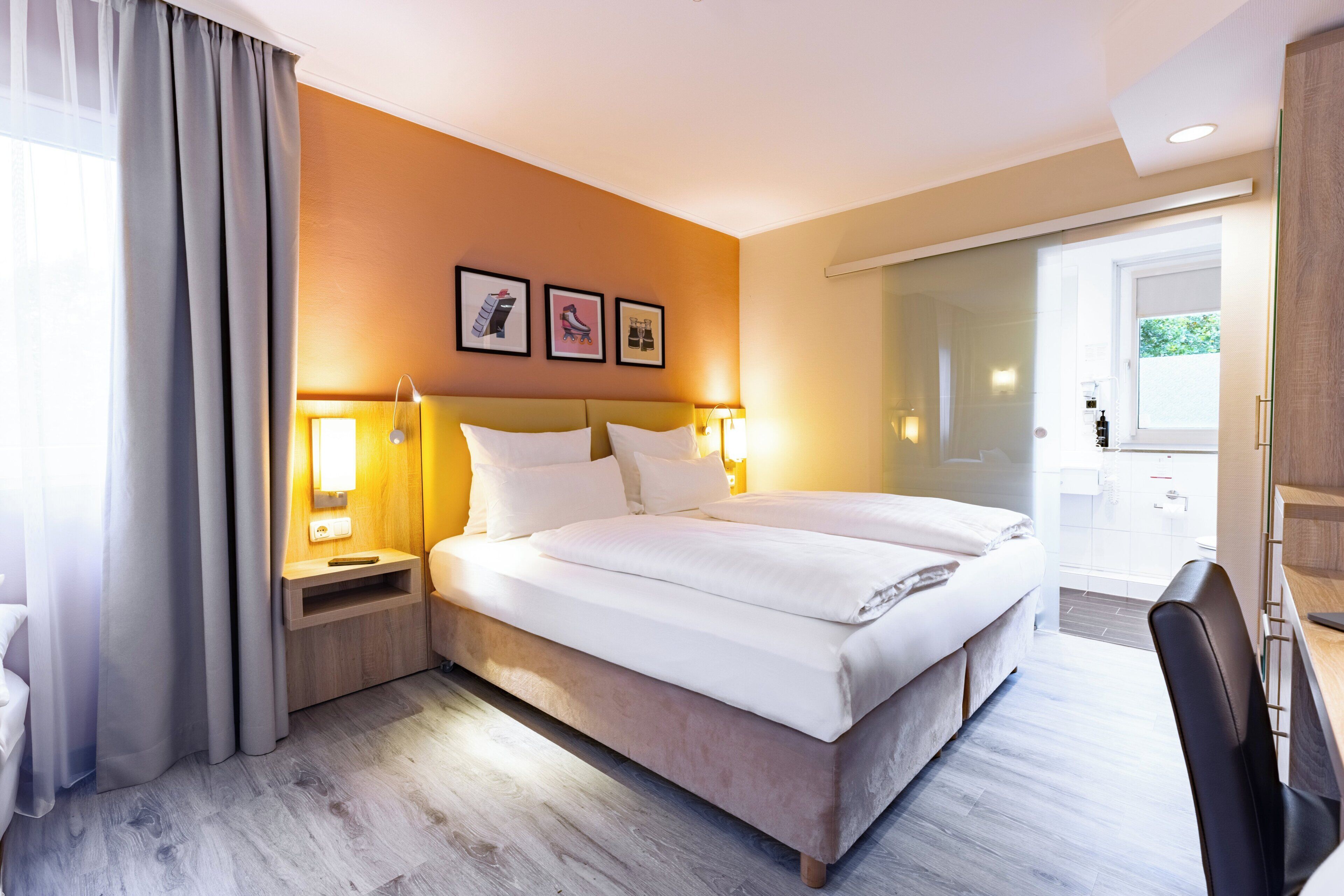 Una habitación de hotel con una cama grande, mesitas de noche con lámparas, un escritorio y una silla.