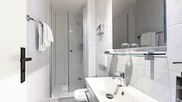 A modern bathroom with a glass shower enclosure, a white sink with a mirror above, and a toilet.