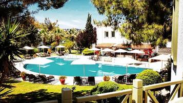 Una piscina al aire libre, sombrillas, sillones reclinables de piscina