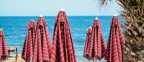 Een privéstrand, ligstoelen aan het strand, parasols, strandlakens