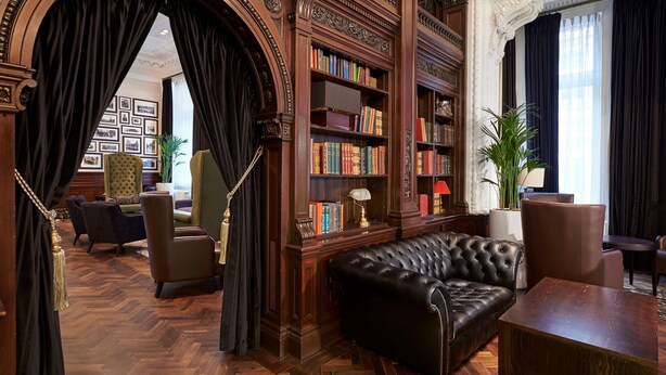 A library with leather sofas, wooden bookshelves, and a herringbone-patterned floor. - DoubleTree By Hilton Hotel & Spa Liverpool (Liverpool)