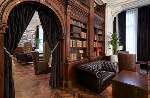 A library with leather sofas, wooden bookshelves, and a herringbone-patterned floor. - DoubleTree By Hilton Hotel & Spa Liverpool (Liverpool)