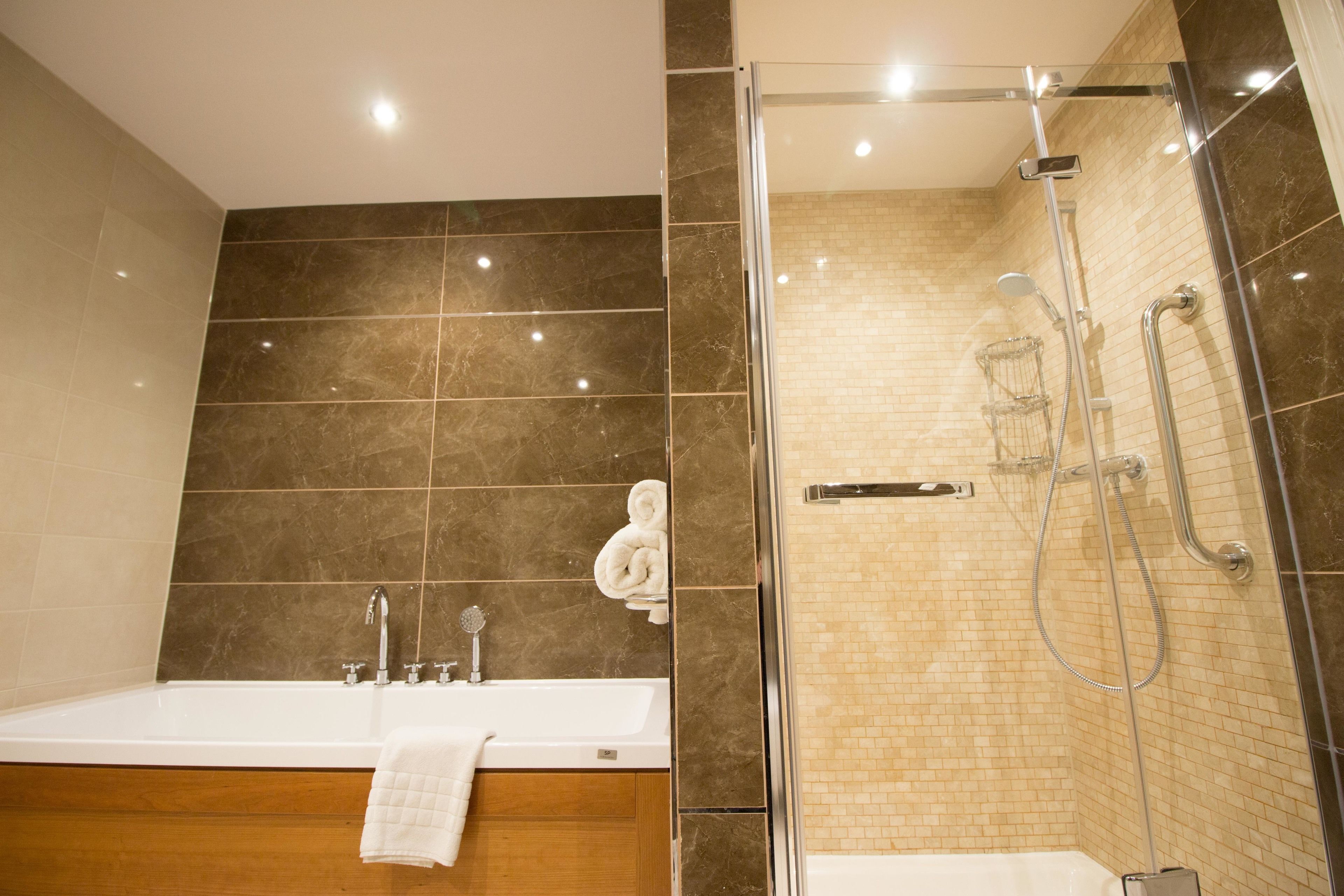 A modern bathroom with a bathtub, a glass-enclosed shower, and a wooden vanity.