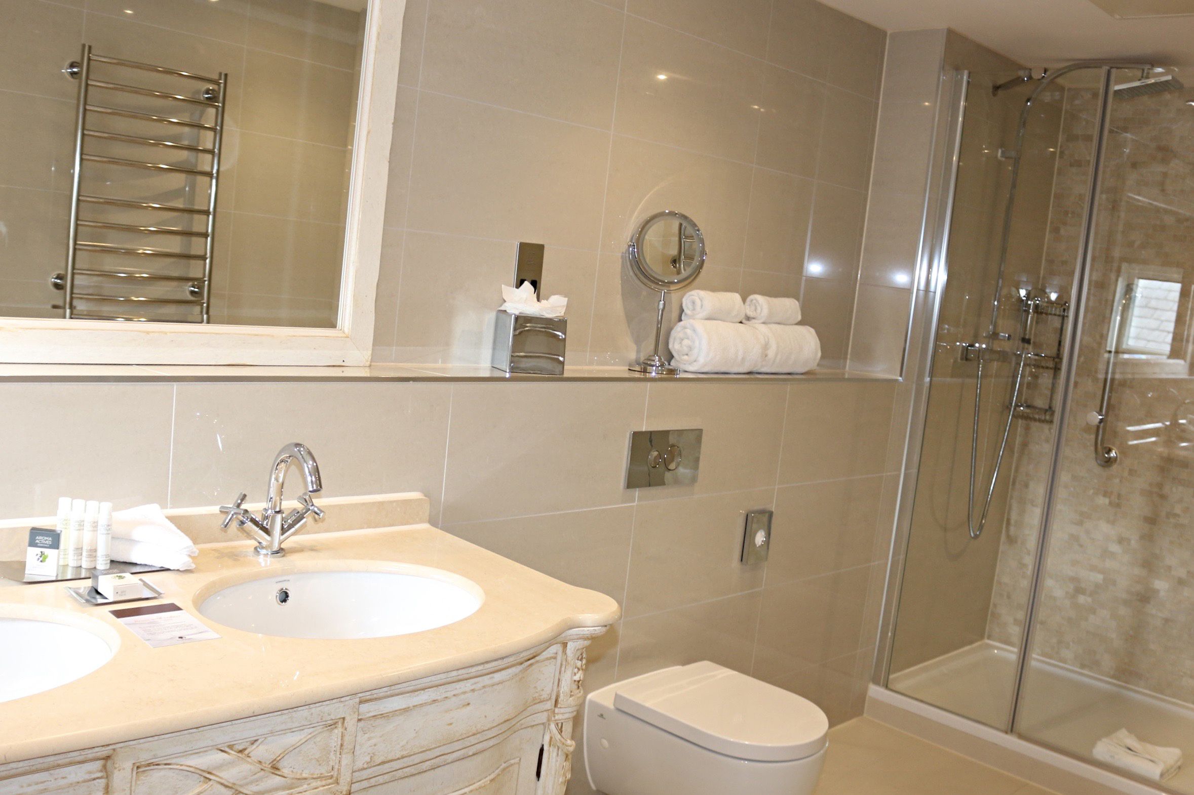 A bathroom with a sink, mirror, towel rack, and shower.