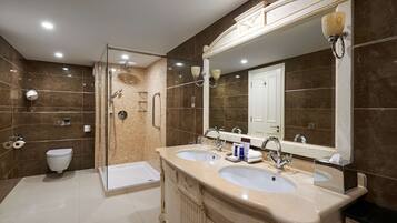 A modern bathroom with two sinks, a glass shower enclosure, a toilet, and a large mirror.