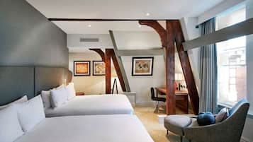 A hotel room with two beds, a desk, a chair, and artwork on the walls.