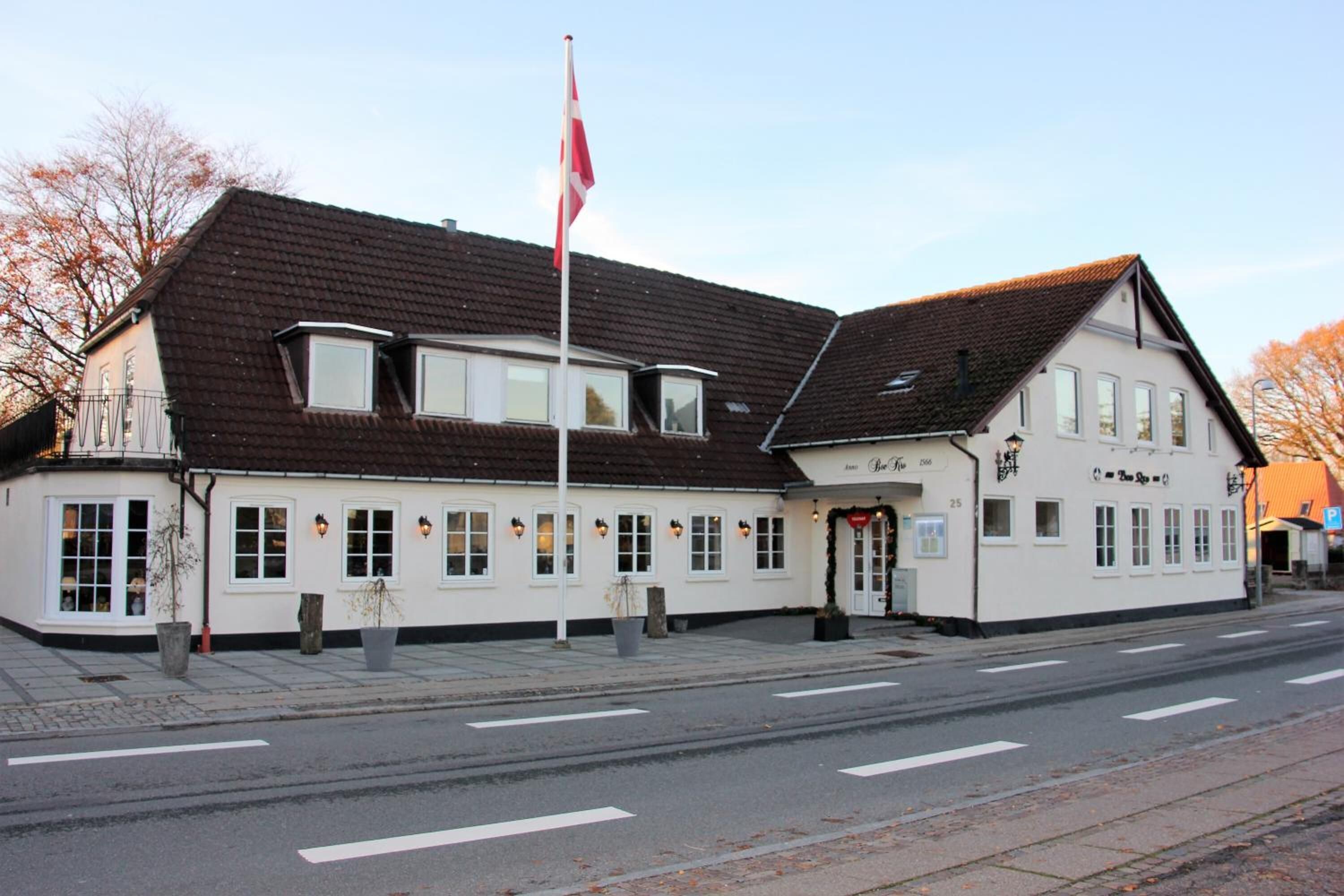 Ein weißes Gebäude mit einem braunen Dach, einer Fahnenstange und einem Schild mit der Aufschrift "The Three Suns".
