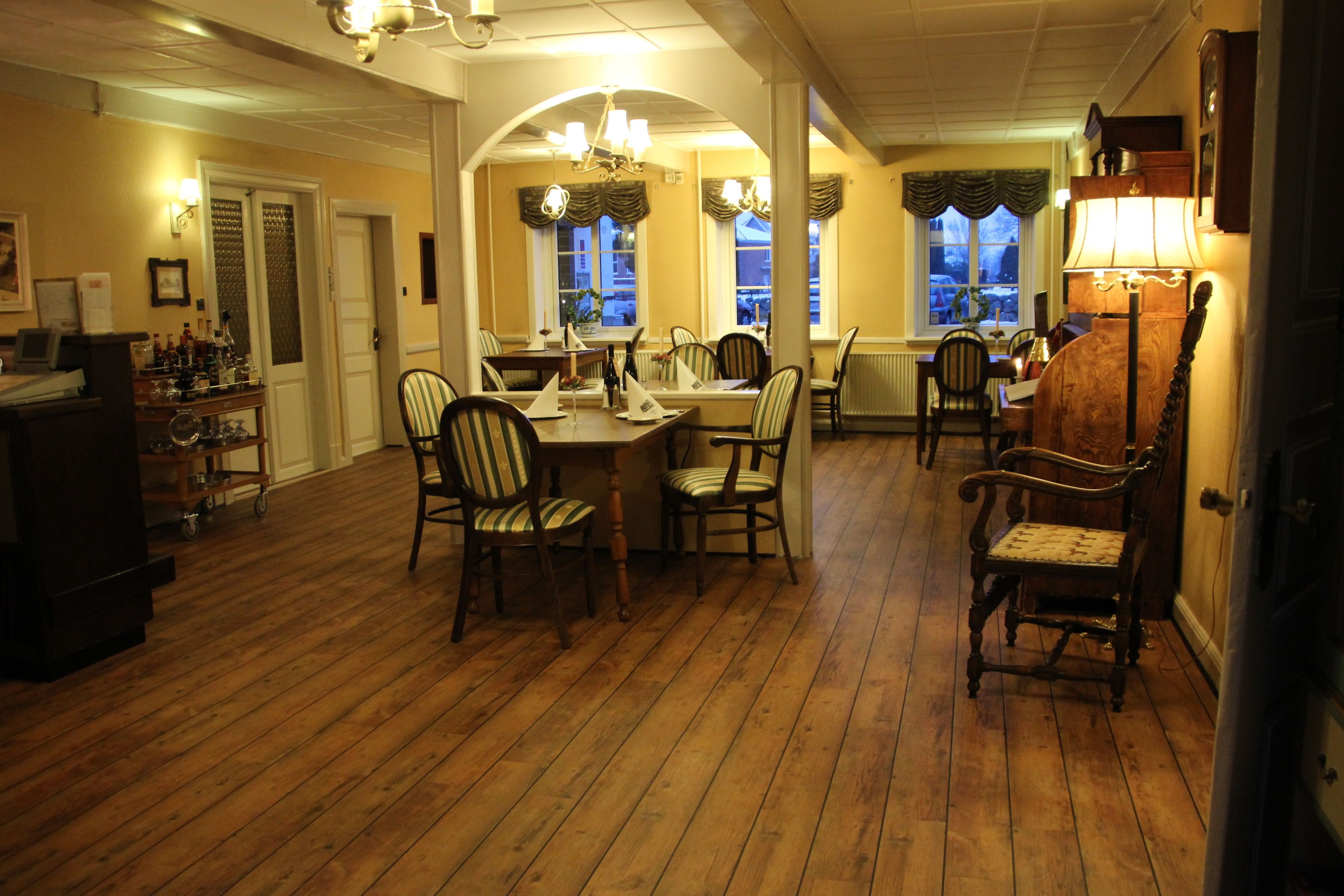 A dining area with wooden flooring, multiple chairs, a table, and a chandelier.