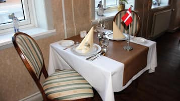 A dining table set with white tablecloth, plates, glasses, and a flag.
