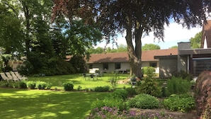 A well-maintained garden with a lawn, outdoor seating area, and a building with a tiled roof. - Bov Kro (Padborg)