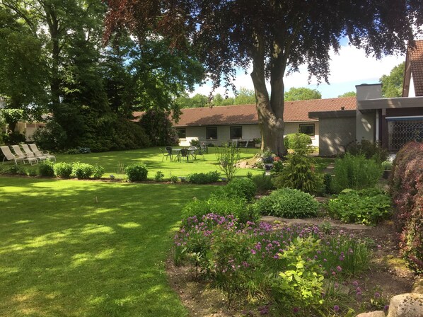 A well-maintained garden with a lawn, outdoor seating area, and a building with a tiled roof.