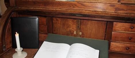 Un escritorio de madera con un libro, una vela y una pequeña fotografía.