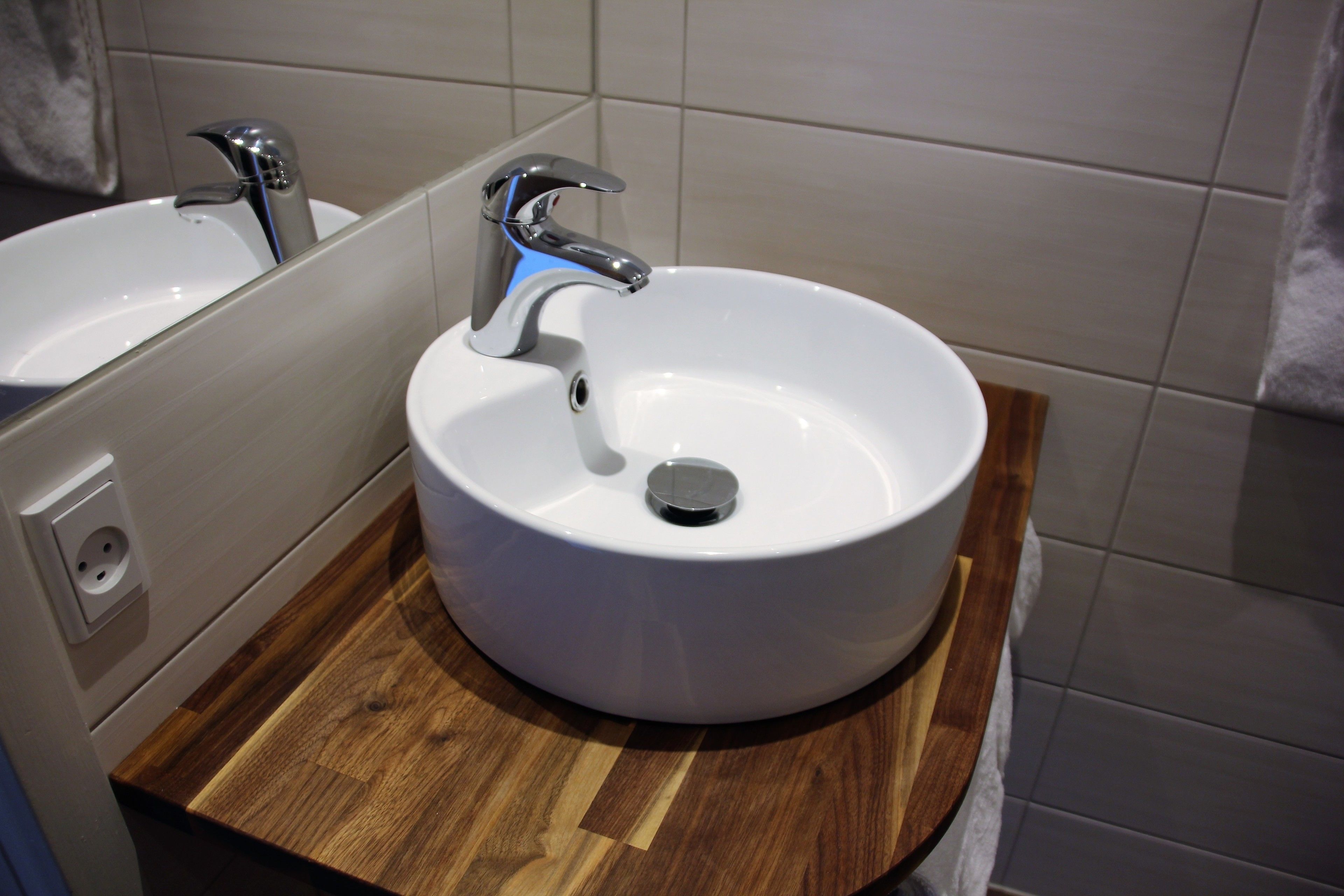 A bathroom with a white sink and a wooden countertop.