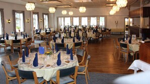 A large dining hall with round tables set for a meal, featuring blue napkins and white tablecloths. - Bov Kro (Padborg)