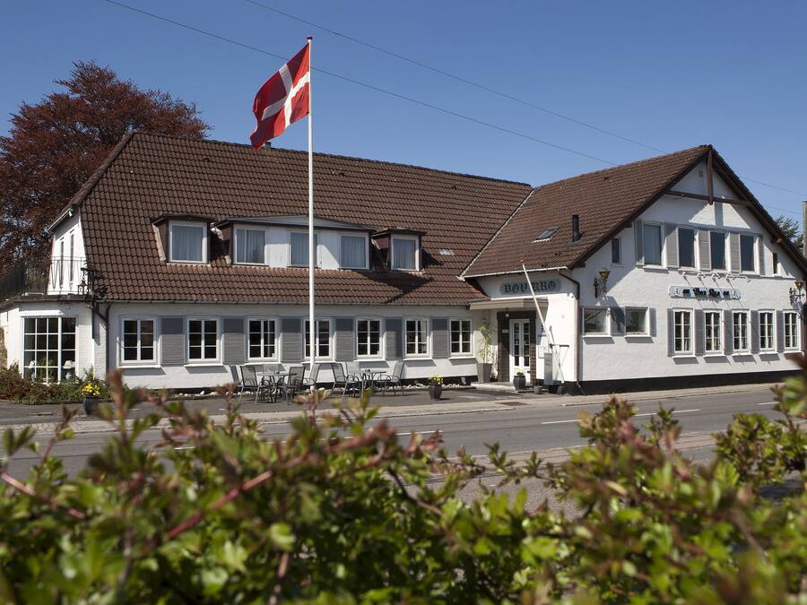 Ein zweistöckiges Gebäude mit Ziegeldach und einer Fahnenstange mit Wimpel.
