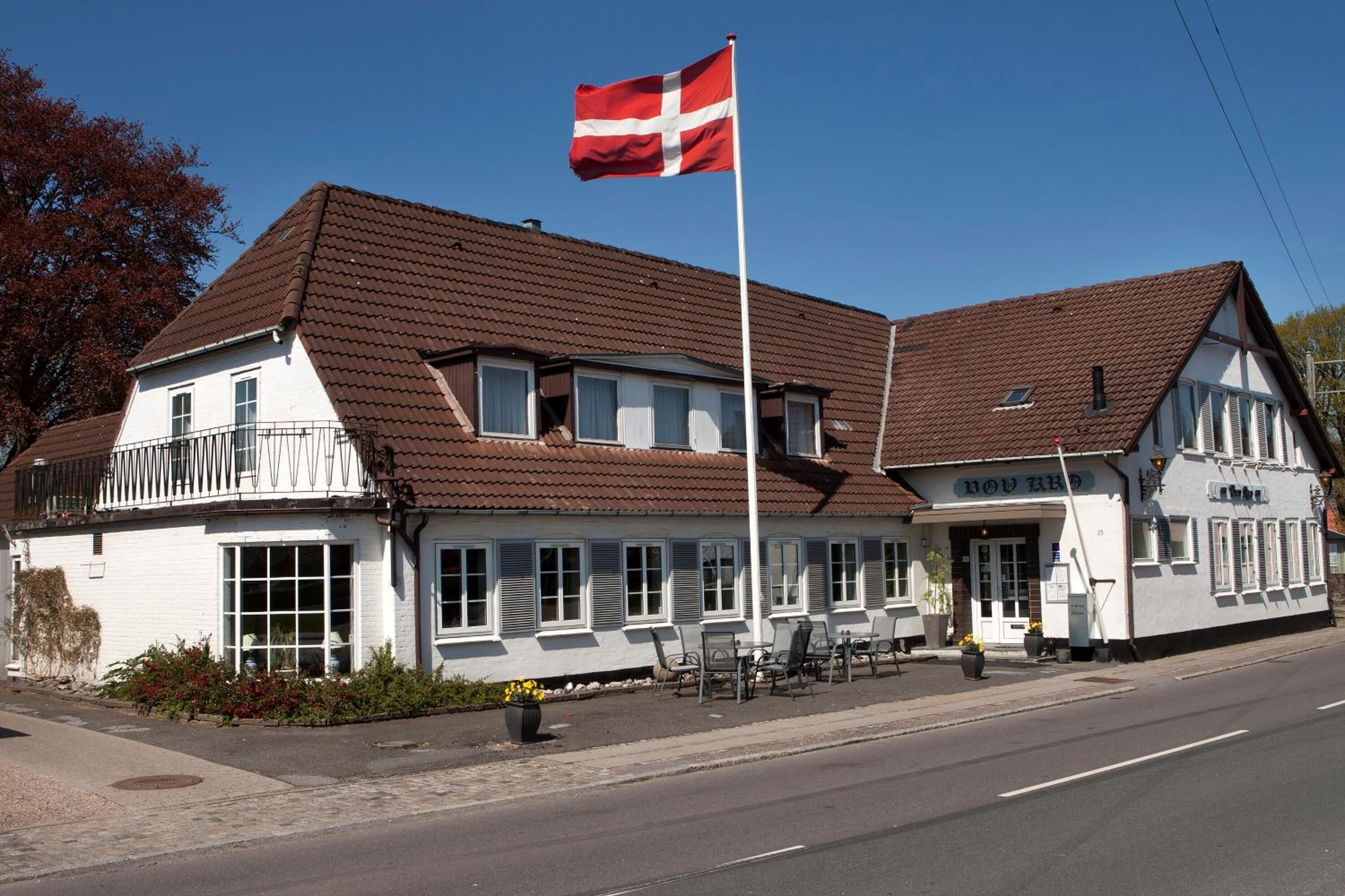A two-story building with a red flag, a balcony, and a sign that reads "Hotel".