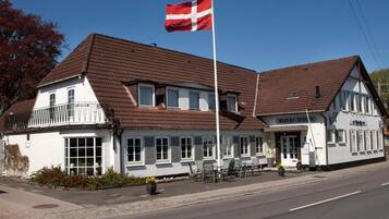 En tvåvåningsbyggnad med en röd flagga, en balkong och en skylt där det står ”Hotell”.