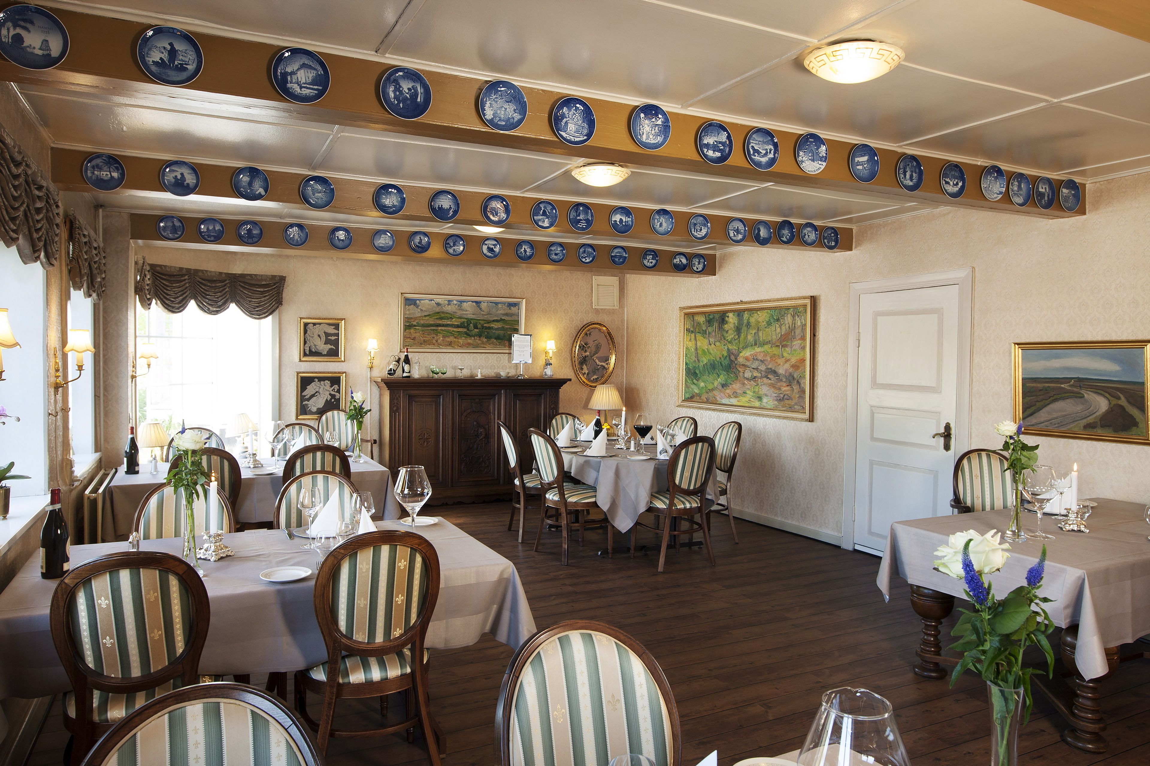 A dining area with multiple tables, chairs, and a decorative ceiling with blue plates.