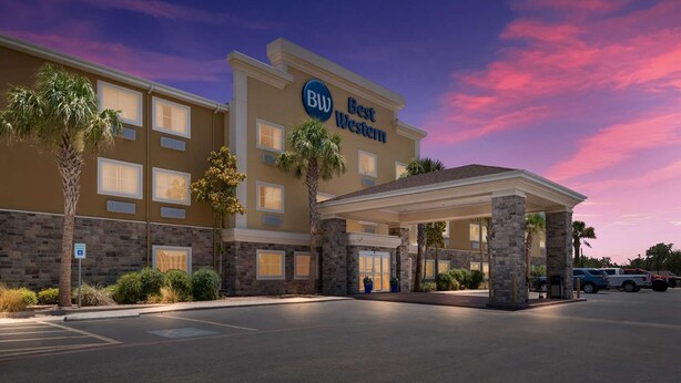 Un hotel Best Western con entrada cubierta, palmeras y estacionamiento.