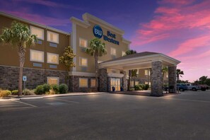 Un hotel Best Western con entrada cubierta, palmeras y estacionamiento.